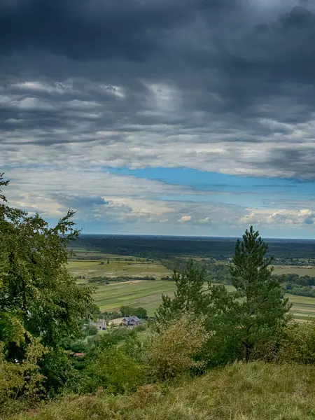 Dramatik bulutlu gökyüzünün altındaki köyün tepe manzarası. Yağmurdan önce kırsal köy manzarası