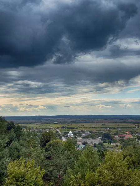 Dramatik bulutlu gökyüzünün altındaki köyün tepe manzarası. Yağmurdan önce kırsal köy manzarası