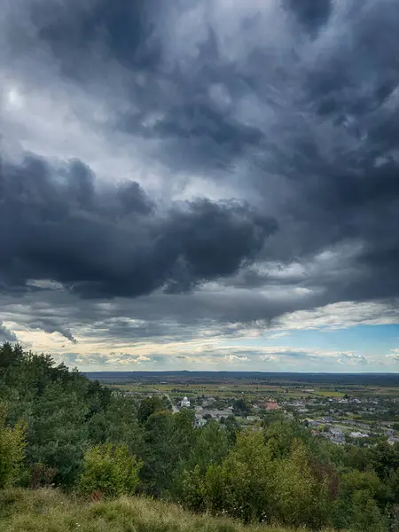 Dramatik bulutlu gökyüzünün altındaki köyün tepe manzarası. Yağmurdan önce kırsal köy manzarası