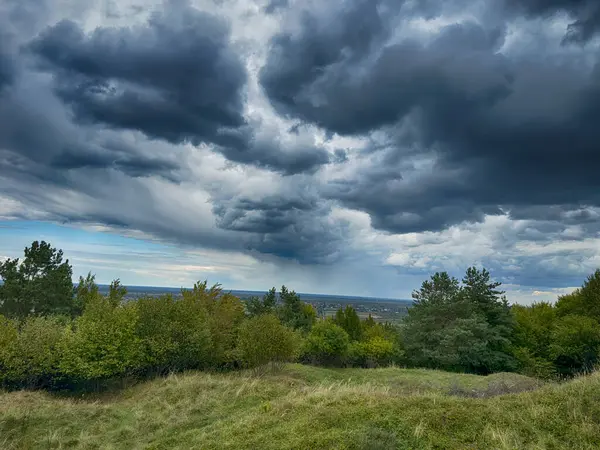 Dramatik bulutlu gökyüzünün altındaki köyün tepe manzarası. Yağmurdan önce kırsal köy manzarası
