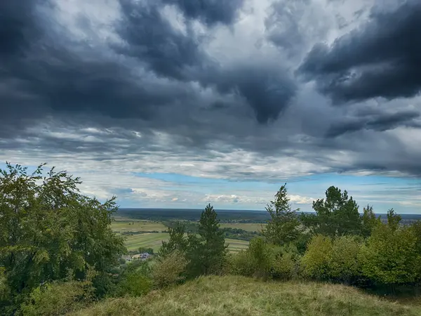 Dramatik bulutlu gökyüzünün altındaki köyün tepe manzarası. Yağmurdan önce kırsal köy manzarası