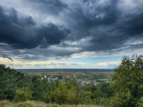 Dramatik bulutlu gökyüzünün altındaki köyün tepe manzarası. Yağmurdan önce kırsal köy manzarası