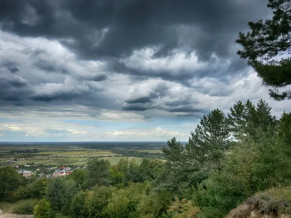 Dramatik bulutlu gökyüzünün altındaki köyün tepe manzarası. Yağmurdan önce kırsal köy manzarası