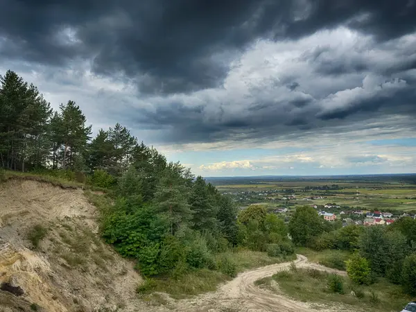Dramatik bulutlu gökyüzünün altındaki köyün tepe manzarası. Yağmurdan önce kırsal köy manzarası