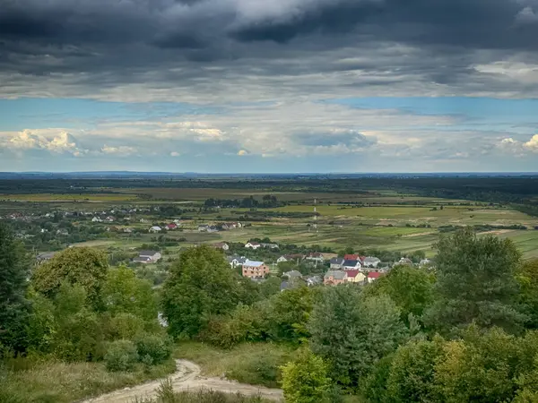 Dramatik bulutlu gökyüzünün altındaki köyün tepe manzarası. Yağmurdan önce kırsal köy manzarası