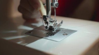 Operatör dikiş makinesinin ayağını temizliyor..