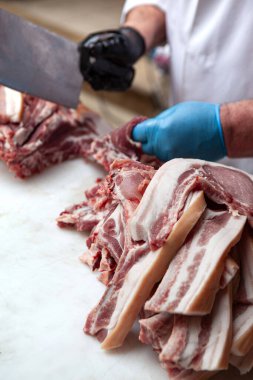 Kasap tezgahta domuz pirzolası kesiyor.