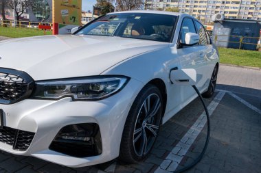 Şarj istasyonundan beyaz bir elektrikli arabayı teşvik etme süreci. Yüksek kalite fotoğraf