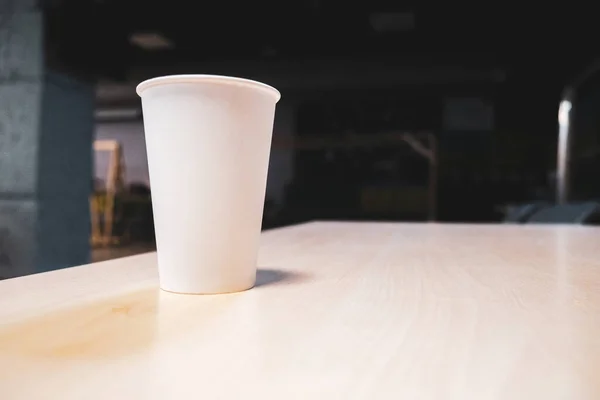 White paper cup on a table in an office center. High quality photo