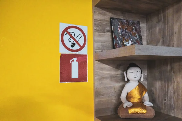 禁止吸烟标志 并禁止在附有玩具佛像的电影附近的白墙上安装灭火器 高质量的照片 — 图库照片