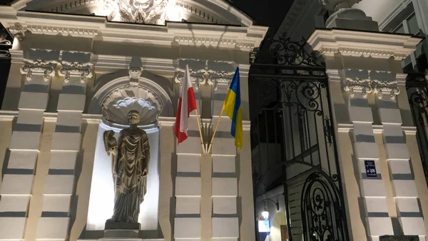 Flags of Ukraine and Poland on a house with a statue in Warsaw, Poland. High quality photo