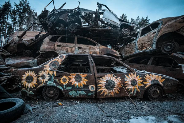 Graffiti with sunflowers on cars shot by Russian occupiers in the Ukrainian city of Bucha. High quality photo