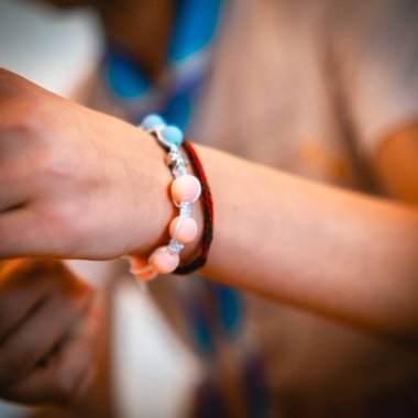 Yumuşak odaklı arka plana karşı canlı boncuklu bileklikler sergileyen bir kişinin ayrıntılı yakın çekimi