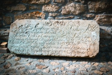 Tarihi bir taş tablet. İçinde karmaşık el yazmaları var. Müzede taş bir duvara yaslanmış..