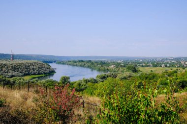 Huzurlu bir nehir, yemyeşil bir arazi ve berrak bir gökyüzünün altında uzak bir ufuk..
