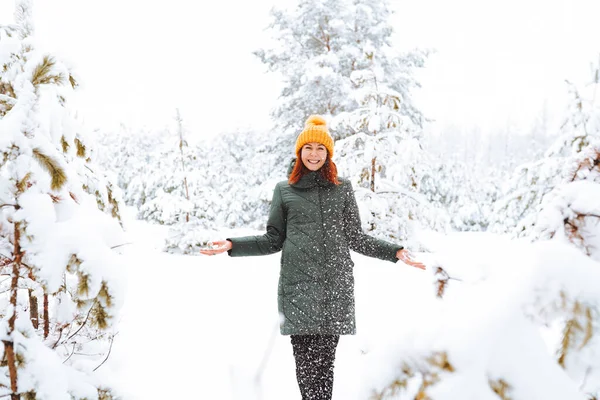 暖かい服の赤い髪をした陽気な女の子は美しい森の近くの屋外で雪と遊ぶ — ストック写真
