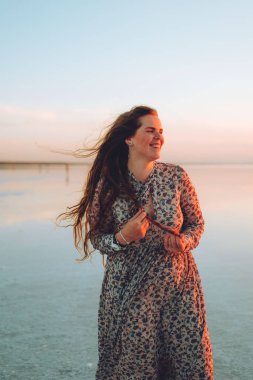 Pembe elbiseli mutlu kadın portresi tuzlu pembe gölün çöl sahilinde eğleniyor. Ukrayna tuz gölü