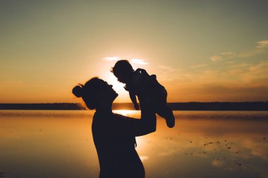 Anne ve oğlu kumsalda gün batımının tadını çıkarıyor..