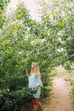 Mutlu hamile kadın yaz günlerinde bahçede mavi elbiseli.