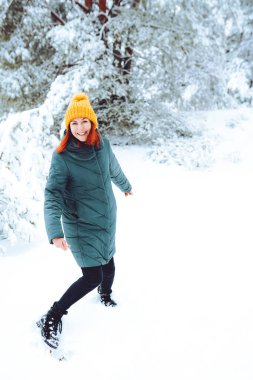 Young beautiful woman in winter forest with fir trees