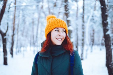 Young beautiful woman in winter forest with fir trees