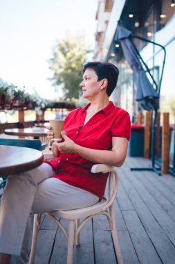 Smiling mature woman drinking coffee outdoors