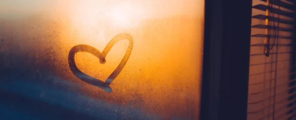 Heart drawn on a misty window during sunset, beautiful banner for Valentines Day