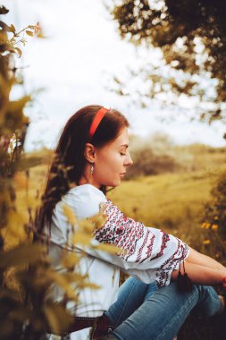 Photo of a smiling young woman in ethnic ukrainian shirt, enjoying the beautiful and peaceful weekend getaway