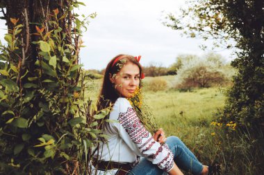 Photo of a smiling young woman in ethnic ukrainian shirt, enjoying the beautiful and peaceful weekend getaway
