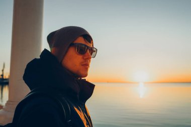 Deniz kenarında gün batımını izleyen, özgürlüğün ve hayatın tadını çıkaran, seyahat yaşam tarzı konsepti.