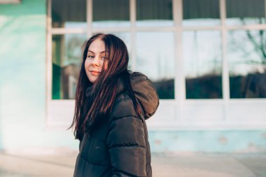 Portrait of young smiling brunette woman in winter jacket looking at camera.