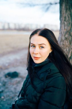Portrait of young smiling brunette woman in winter jacket looking at camera.