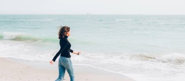 Young cheerful woman enjoing sunny day on the beach.