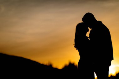 Silhouettes of a tender couple at sunset clipart