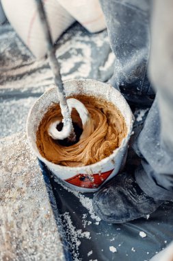 Professional worker mixes two chemical compounds in the metal bucket using the mixer