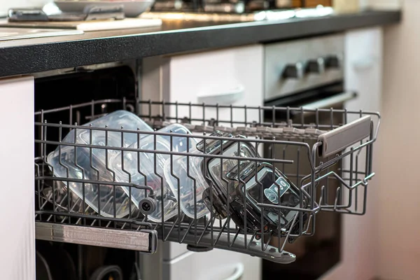 A closeup of plastic containers in a dishwasher, in a kitchen indoors