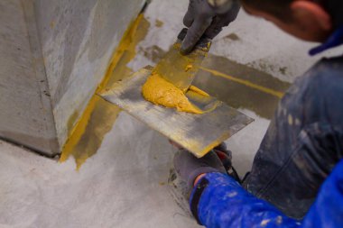 Profesyonel, genişleme eklemlerini mala ve macun bıçağı kullanarak epoksi havan topuyla ustalıkla dolduruyor. Malzemenin düzgün bir şekilde yayılmasını ve eklemi tamamen doldurmasını sağlıyor.