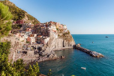 Manarola, İtalya 'nın bir kıyı kasabası, deniz manzaralı dik yamaçlar boyunca uzanan renkli evleri gözler önüne seriyor, önlerinde küçük bir liman ve kayıklar, ve ufka doğru uzanan mavi sular.