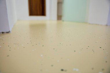 Yeni dekoratif epoksi döşemeleri olan bir tıbbi tesis. Kusursuz yüzeyde gömülü renkli çipler canlı ve dayanıklı bir çözüm yaratır. Seçici odak