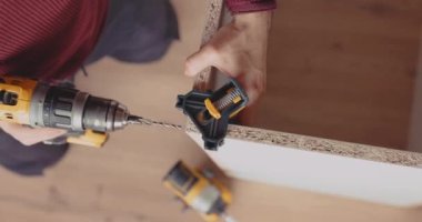 Yetenekli bir adam oturma odasında kablosuz elektrikli tornavida ve vidalar için matkap kullanıyor..