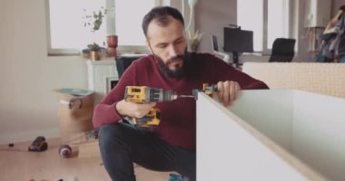 Yetenekli bir adam oturma odasında kablosuz elektrikli tornavida ve vidalar için matkap kullanıyor..