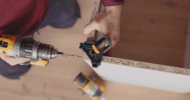 熟練した男は コードレス電動ドライバーを使用してリビングルームに家具を構築し ネジのための事前掘削 — ストック動画