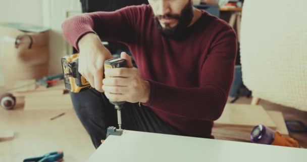 強力なコードレス電気自動車のドライバーを使って家で家具を組み立てる熟練した男 — ストック動画