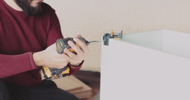 強力なコードレス電気自動車のドライバーを使って家で家具を組み立てる熟練した男 — ストック動画