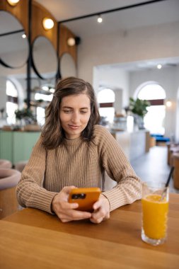 Elinde cep telefonuyla gülümseyen genç bir kadın..