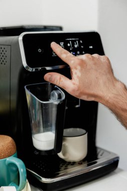 Arka planda ustensiller olan kahve makinesini çalıştıran Vitiligo hastası bir erkek.