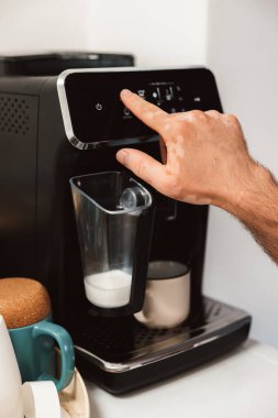 Arka planda ustensiller olan kahve makinesini çalıştıran Vitiligo hastası bir erkek.