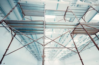 İnşaat işçilerinin tavan ve aydınlatma için yüksek çalışma platformları sağlayan metal iskeleler.
