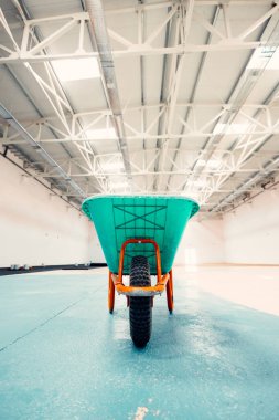 Boş bir el arabası kullanılmayı bekleyen boş bir sanayi binasının ortasında duruyor.