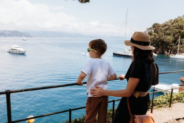Portofino limanına bakan bir terasta duran anne ve oğul güneşli bir günün tadını çıkarıyorlar.